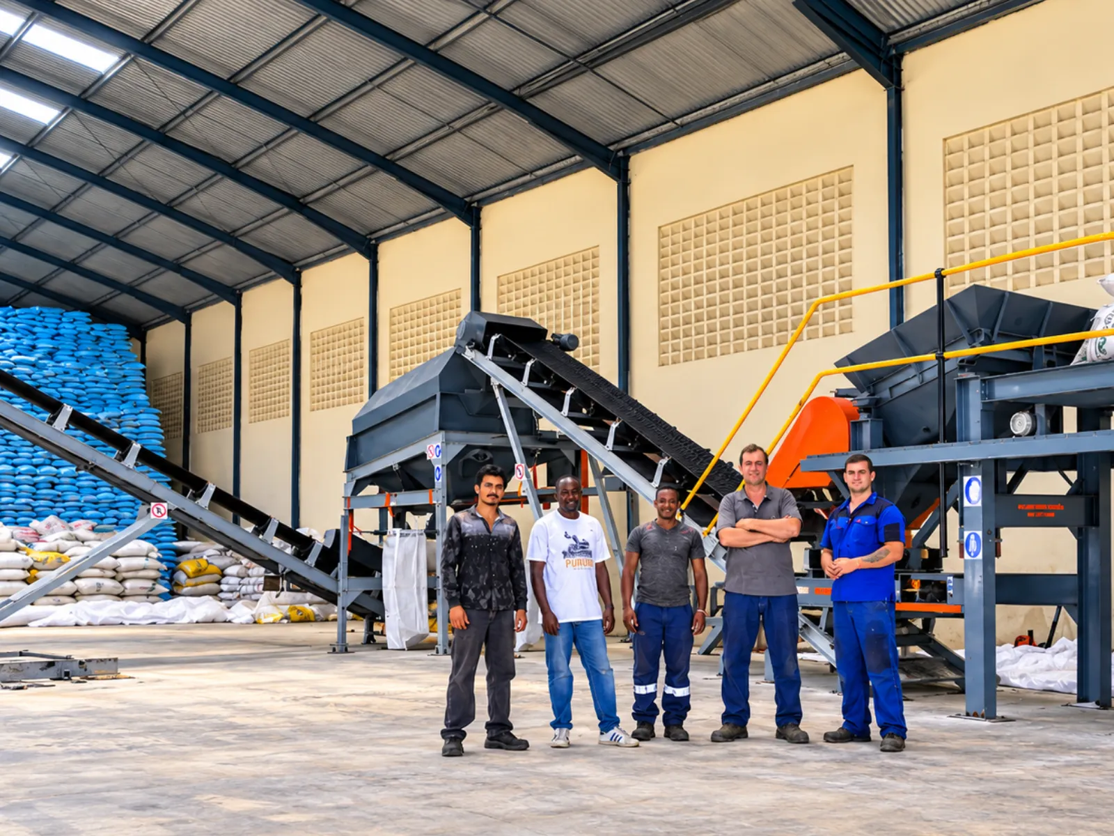 Technical team standing beside fertilizer processing equipment inside an industrial plant