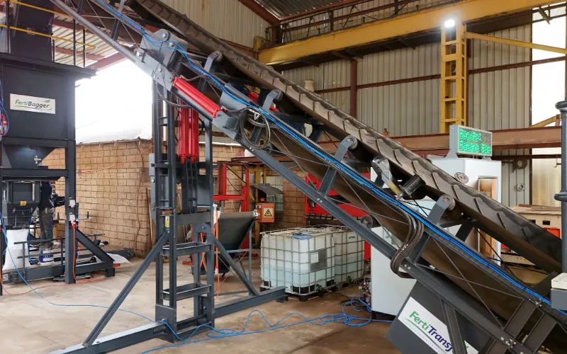 Custom fertilizer conveyor integrated with bagging and transfer equipment in a processing plant